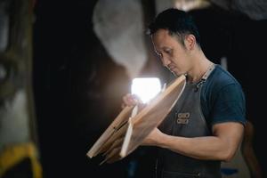 Gitarrenbauer asiatischer Mann, der Akustikgitarren im Labor herstellt. asiatischer gitarrenbauer baut hochwertige gitarren für musiker handgefertigter gitarrenshop. Arbeiten mit feiner Holzmusik, Tradition, altem Handwerk. foto