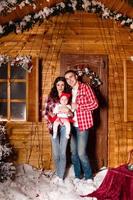 mama und papa posieren mit ihrer charmanten kleinen tochter im geschmückten weihnachtsstudio. Neujahrs Fotoshooting. foto