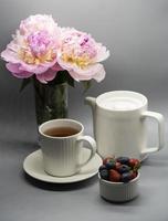 Tasse Tee, Pfingstrose und Beeren foto