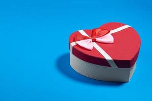 eine Postkarte aus einer Schachtel in Form eines Herzens und Rosenknospen. Valentinstag-Konzept foto