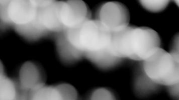 verschwommenes weißes Bokeh des Lichts auf schwarzem Hintergrund in monochromem oder schwarz-weißem Ton. verschwommene Tapete mit grüner Beleuchtung. foto