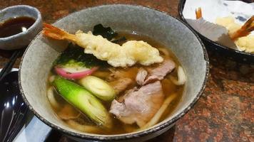 Nahaufnahme von Udon-Nudeln mit Suppe, geschnittenem Schweinefleisch, Algen oder Algen, japanische Frühlingszwiebeln auf Schüssel im japanischen Restaurant. warmes oder asiatisches Essen. foto