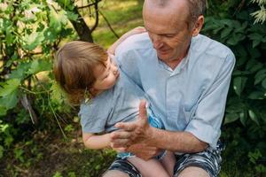 Ein kleines Mädchen umarmt ihren Großvater bei einem Spaziergang im Sommer im Freien. foto