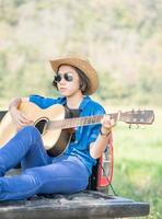 Frau trägt Hut und spielt Gitarre auf Pickup-Truck foto