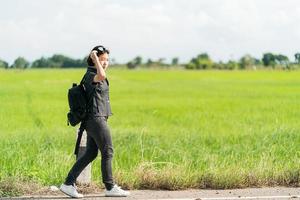 Frau mit Rucksack per Anhalter entlang einer Straße foto