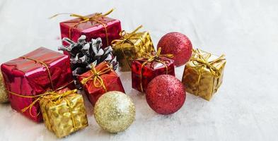 goldene und rote Weihnachtsgeschenke und Bälle im Schnee