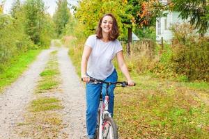 junge frau, die fahrrad im sommerstadtpark draußen fährt. aktive Menschen. Hipster-Mädchen entspannen und Fahrrad fahren. Radfahren zur Arbeit am Sommertag. fahrrad- und ökologie-lifestyle-konzept. foto