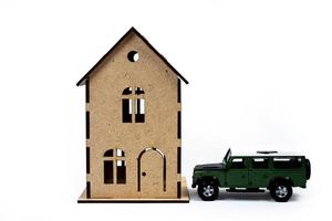 Haussymbol mit Metallschlüssel auf weißem Hintergrund. immobilien, versicherungskonzept, hypothek, hauskauf, immobilienmaklerkonzept, kleine autos, bäume foto