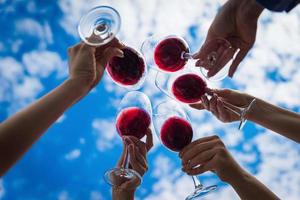 Menschen, die auf der Sommerterrasse des Cafés oder Restaurants mit Wein anstoßen foto