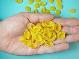 muschelförmige Nudeln fallen aus Ihrer Hand. italienisches Essen. Küche der Völker der Welt. Hartweizen foto