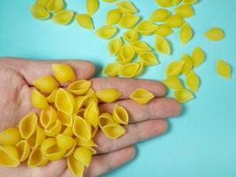 muschelförmige Nudeln fallen aus Ihrer Hand. italienisches Essen. Küche der Völker der Welt. Hartweizen foto