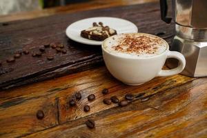 Heißer Cappuccino in weißer Tasse mit Holzhintergrund, Kaffee ist ein beliebtes Getränk auf der ganzen Welt. foto