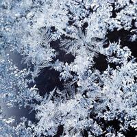 Schneeflocken und Frostmuster auf Glas hautnah foto