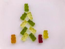 Weihnachtsbaum aus weißen und grünen Gummibärchen. neben einem weihnachtsbaum leuchtende bären aus gelatine. leckeres und saftiges Dessert. weihnachten, frohes neues jahr foto