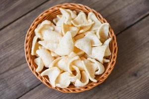 Garnelen-Cracker-Chips auf Korb- und Holztischhintergrund - hausgemachte knusprige Garnelen-Cracker oder Garnelen-Knusperreis für traditionellen Snack foto