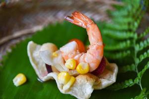 Garnelensalat, Mais und Sauce auf Garnelencrackern mit Bananenblatthintergrund asiatisches Essen in thailändisch - leckeres Menü Garnelen gekocht foto