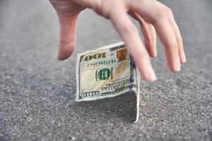 Handpflücken Sie eine hundert-Dollar-Banknote vom Boden. Geldkonzept gefunden foto