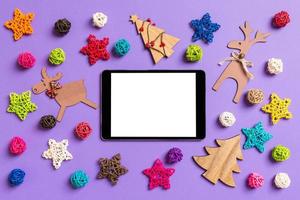 Draufsicht des digitalen Tablets. neujahrsdekorationen auf lila hintergrund. festliche Sterne und Bälle. Frohe Weihnachten-Konzept foto