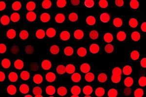 Unfokussiertes abstraktes rotes Bokeh auf schwarzem Hintergrund. defokussiert und verschwommen viele runde licht foto