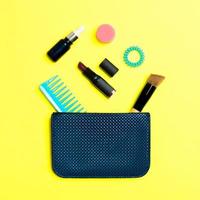 Make-up-Produkte, die aus der Kosmetiktasche auf gelbem Hintergrund mit leerem Platz für Ihr Design verschüttet werden foto