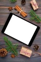 digitales tablet-modell mit rustikalen weihnachtlichen hölzernen hintergrunddekorationen für app-präsentation. draufsicht mit kopierraum foto