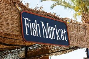 Schild des Fischmarktes im Freien. Fischmarktschild am Strand mit Palme foto