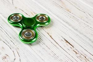 grüner Fidget Spinner Stressabbau Spielzeug auf Holz Hintergrund foto