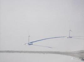 luftaufnahme der weißen schneebedeckenden stadt und der modernen windkraftanlage im winter, schneelandschaftstapete, stadt in weiß, skandinavien, arktischer kreis foto