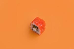 California-Maki-Sushi-Rolle mit Kaviar auf orangefarbenem Hintergrund. minimalismus draufsicht flach lag mit japanischem essen foto