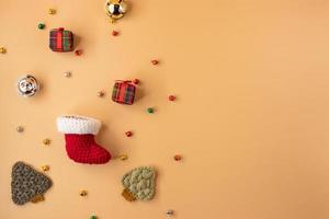 handgefertigter Häkelstrumpf, Geschenk und Weihnachtsbaum auf orangefarbenem Pastellhintergrund. Konzept der frohen Weihnachten und des guten Rutsch ins neue Jahr. foto