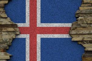 Island-Flagge in Lackfarben auf der alten Steinmauer in der Nähe dargestellt. strukturiertes banner auf felswandhintergrund foto