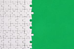 Fragment eines gefalteten weißen Puzzles auf dem Hintergrund einer grünen Kunststoffoberfläche. texturfoto mit kopierraum für text foto