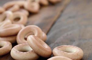 viele frische gelbe bagels liegen auf der oberfläche des alten dunklen holzes. eine beliebte Art von Mehlprodukten. eine der traditionellen russischen Leckereien für Tee foto