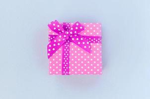 kleine lila geschenkbox mit band liegt auf violettem hintergrund foto