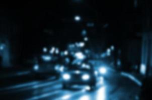 verschwommene Nachtszene des Verkehrs auf der Fahrbahn. defokussiertes Bild von Autos, die mit leuchtenden Scheinwerfern fahren. Bokeh-Kunst foto