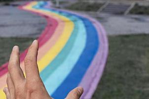 menschliche hand, die einen regenbogenpfad auf der stadtstraße freigibt, kopierraum, liebe, freiheit und freundschaft, abstrakt foto