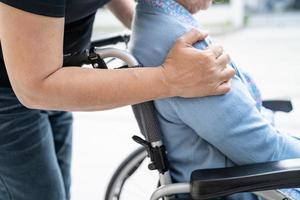 Pflegekraft hilft und pflegt asiatische Senioren oder ältere Frauen, die im Rollstuhl auf der Krankenstation sitzen, gesundes, starkes medizinisches Konzept foto