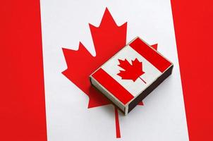 Die Kanada-Flagge ist auf einer Streichholzschachtel abgebildet, die auf einer großen Flagge liegt foto