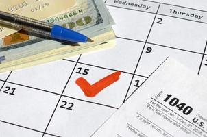 1040 individuelle Einkommensteuererklärung leer mit Kreditkarte auf Dollarnoten und Stift auf Kalenderblatt mit markiertem 15. April foto