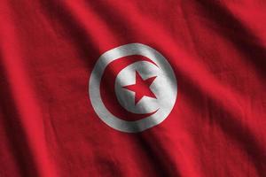 tunesische flagge mit großen falten, die im innenbereich unter dem studiolicht wehen. die offiziellen symbole und farben im banner foto