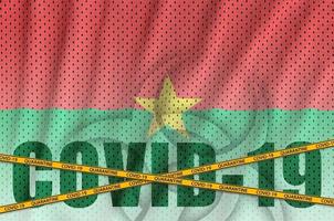 burkina faso flagge und covid-19-inschrift mit orangefarbenem quarantäne-grenzband. Coronavirus- oder 2019-ncov-Viruskonzept foto