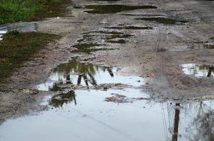 Foto eines Fragments einer zerstörten Straße mit großen Pfützen bei Regenwetter