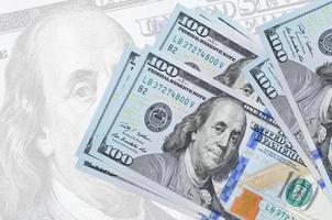 100 US-Dollar-Scheine liegen im Stapel auf dem Hintergrund einer großen halbtransparenten Banknote. abstrakte Darstellung der Landeswährung foto