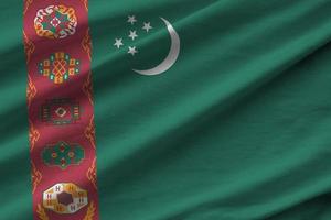 turkmenische flagge mit großen falten, die unter dem studiolicht im innenbereich wehen. die offiziellen symbole und farben im banner foto