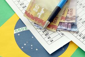 Stift mit brasilianischen Geldscheinen auf dem Lotteriespiel. Konzept von Glück und Glücksspiel in Brasilien foto