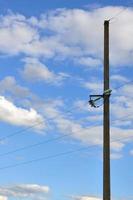 Betonmast mit Drähten der Stromleitung vor dem Hintergrund des blauen bewölkten Himmels foto