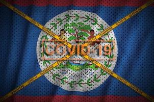 belize-flagge und covid-19-stempel mit orangefarbenem quarantäne-grenzbandkreuz. Coronavirus- oder 2019-ncov-Viruskonzept foto