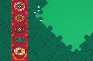 Die turkmenische Flagge ist auf einem fertigen Puzzle mit freiem Platz für grüne Kopien auf der rechten Seite abgebildet foto