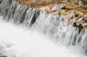 ein kleiner Wasserfall. Der Höhenunterschied des Wasserflusses im Fluss ist mit Rundholzstämmen ausgestattet foto