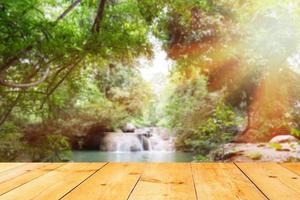 Holzbrett über verschwommenem Wasserfall und Wald foto